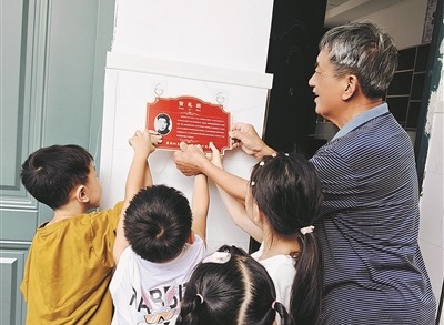 蒋贤礼烈士的儿子蒋义生,与楂林小学“贤礼班”学生一起挂“英烈牌”。季俊磊摄