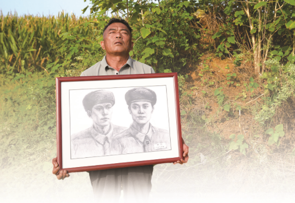 陈为村抱着烈士陈淑彬兄弟俩的画像,在太爷爷太奶奶坟前百感交集。