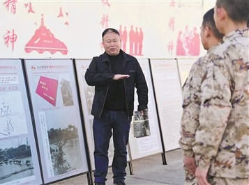 影像展现场，李森亮在“烽火岁月”展区的抗战影像史料展板前，为官兵讲述侵华日军的残暴行径。殷  超摄