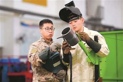 王江帆（左）正在向新同志传授焊接经验。刘明松摄