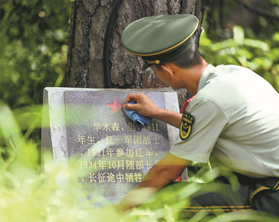 该支队一名战士擦拭位于“红军村”后山的烈士墓碑。