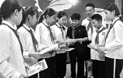 杨素香（右四）看学生绘制的手抄报。